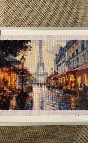 Handmade cross stitch artwork featuring a Paris street scene with the Eiffel Tower